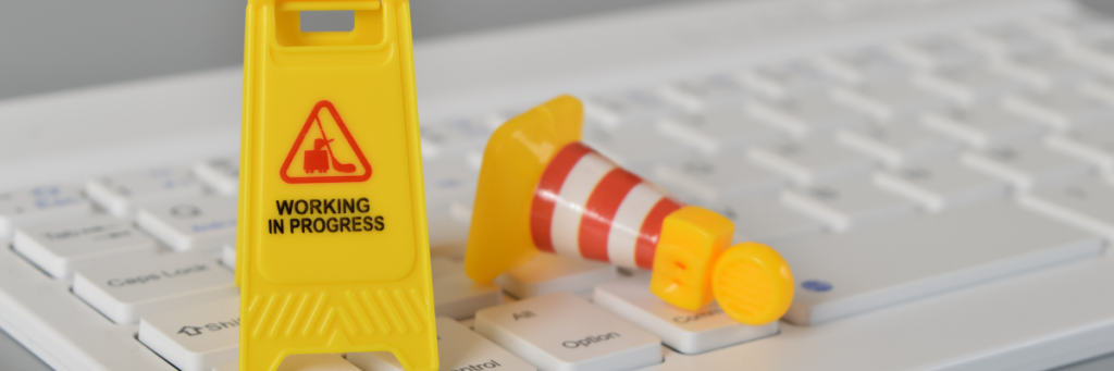 Yellow 'caution' sign on a white keyboard that says 'working in progress' - a little humour for when you redesign your website